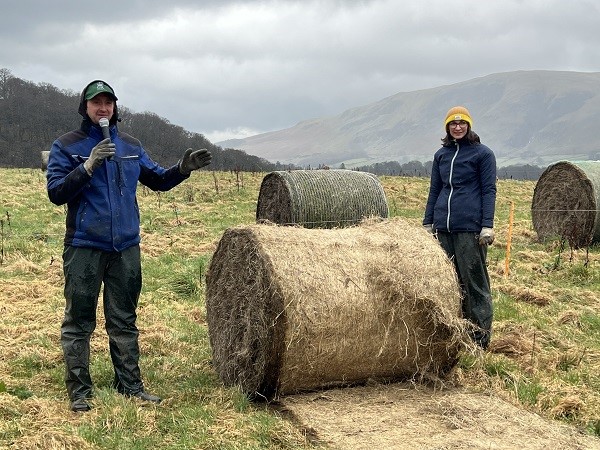Sam and Claire Beaumont standing next to a hay bale